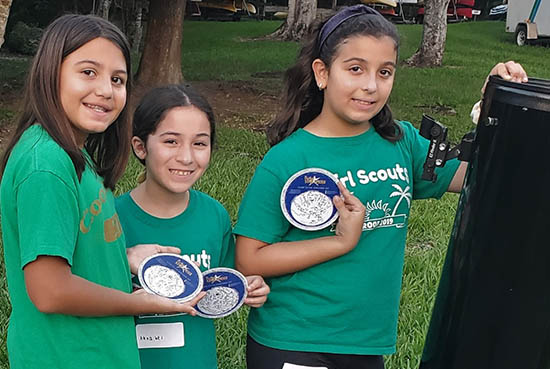 3 girl scouts holding star charts
