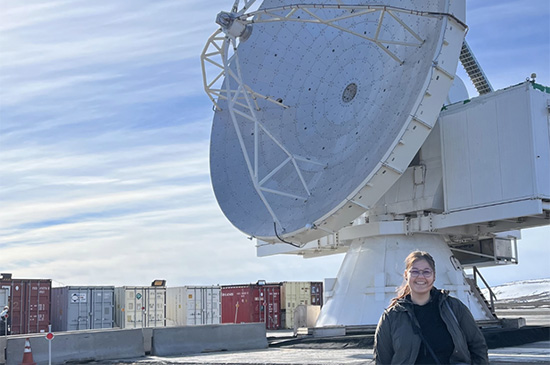 Photo of a woman standing in front of a large radio astronomy dish